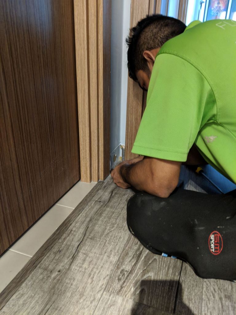 The Floor Xpert guy using a penknife to cut the damaged skirting parts and pull them out.